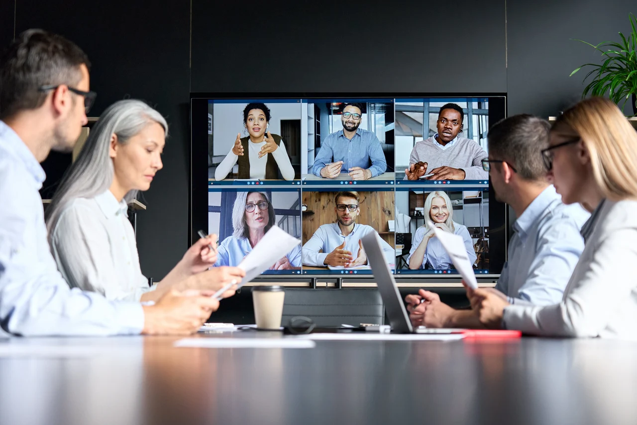 Business partners collaborating across an office and a video conference
